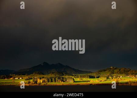 Hopfensee mit stürmischem Himmel im sanften Morgenlicht und Allgäu-Bergen im Hintergrund, Hopfen am See, Ostallgäu, Schwaben, Bayern, Deutschland Stockfoto