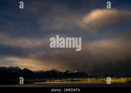 Hopfensee mit stürmischem Himmel im sanften Morgenlicht und Allgäu-Bergen im Hintergrund, Hopfen am See, Ostallgäu, Schwaben, Bayern, Deutschland Stockfoto