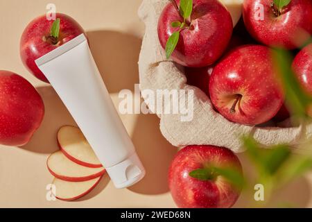 Ein Korb bedeckt mit Handtuch und gefüllt mit mehreren frischen Äpfeln. Unbeschrifteter Kosmetikbehälter für das Branding von Apple (Malus domestica)-Extrakt Stockfoto