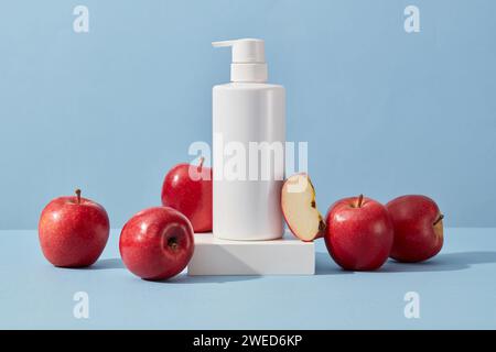 Unbeschriftete Pumpflasche steht auf einem Podium mit einigen Äpfeln. Apfel (Malus domestica) kann tote Hautzellen entfernen Stockfoto
