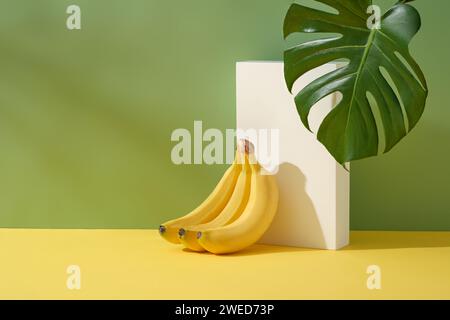 Minimale Szene mit einem Bananenbund, der sich auf einem weißen Podium auf einem rechteckigen Podium stützt. Bananenextrakt (Musaceae) hilft, Aknenarben und dunkle Flecken zu verblassen, während s Stockfoto