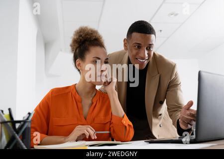 Zwei Kollegen aus den 30er Jahren diskutieren Online-Präsentationen, bereiten Onlineprojekte vor, Stockfoto