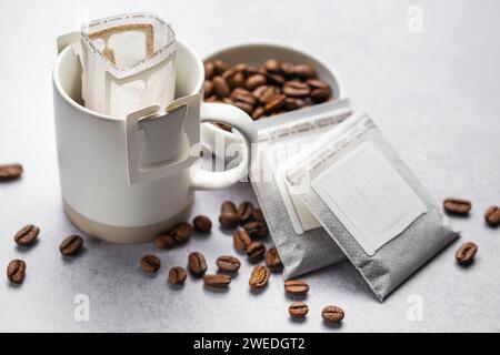 Eine Tasse frisch gebrühten Tropfkaffee. Tropfkaffee-Beutel mit gemahlenem Kaffee zum Brühen in einer Tasse Stockfoto