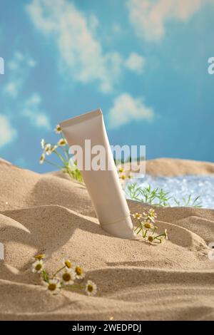 Mockup-Szene für Werbekosmetik mit natürlichem Konzept. Ein leeres weißes Plastikrohr auf Sand mit frischem Fieber und einem kleinen See auf blauem Himmel Stockfoto