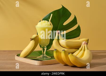 Frische reife Bananen mit Smoothie-Tasse und grünem Blatt auf gelbem Hintergrund. Jeden Tag Bananen zu essen, ist eine einfache, aber äußerst effektive Methode, um sie zu verschönern Stockfoto