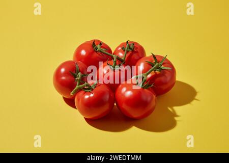 Auf gelbem Hintergrund sind frische, reife Tomaten dekoriert. Tomaten enthalten viele Vitamine A, C und B6, die gut für Haut und Haare sind Stockfoto
