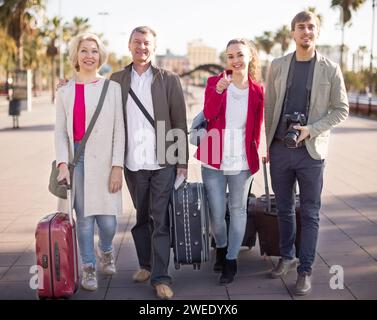 Touristen mit Koffern und Kamera spazieren auf dem Bürgersteig im Hafen der europäischen Stadt Stockfoto