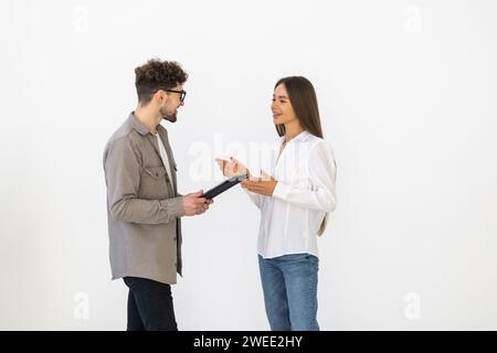 Zwei junge Geschäftsleute, die ein digitales Tablet nutzen, während sie in einem Sitzungssaal stehen. Zwei Geschäftskollegen, die während eines Meetings ein Gespräch führen. Stockfoto