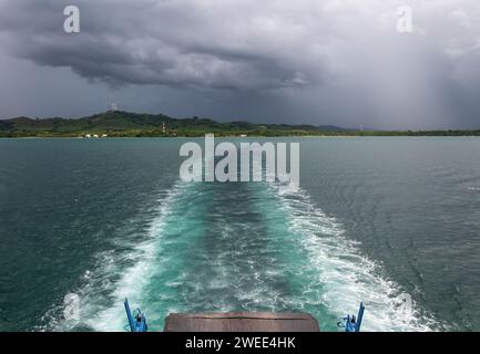 Die Fähre segelt auf dem Meer und hinterlässt bei bewölktem Wetter einen Pfad auf dem Wasser. Stockfoto