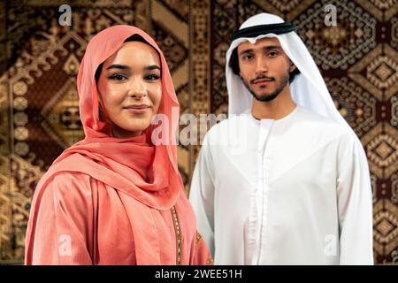 Ein junges Paar aus Emiraten verbringt Zeit in einem traditionellen arabischen Café. Mann und Frau tragen Kandura und Abaya aus Dubai, die sich miteinander unterhalten. Stockfoto