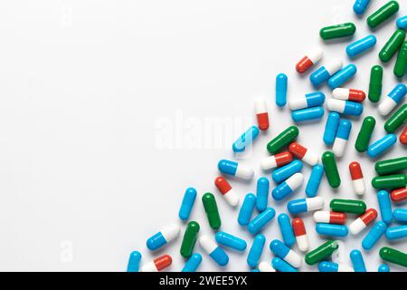 Verschüttete Pillen auf weißem Hintergrund, Draufsicht, Kopierraum. Haufen von Nahrungsergänzungsmitteln, verschiedene bunte Vitamine, verschiedene pharmazeutische medizinische Capsu Stockfoto
