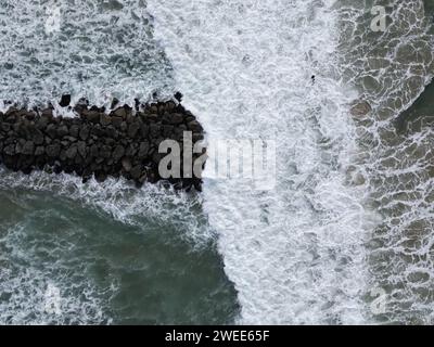 Ein hochauflösendes Luftbild von Wellen, die auf Felsen am Strand treffen Stockfoto