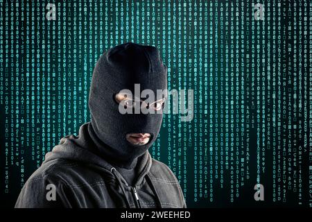 Ein Krimineller trägt schwarze Sturmhaube und Hoodie über blauem Computercode-Hintergrund Stockfoto