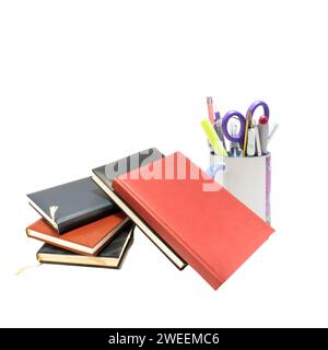 Eine vielfältige Auswahl an Schreibwaren, wie Stifte, Marker und Büroklammern, sind in einem ordentlichen Stapel von Büchern angeordnet Stockfoto