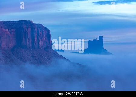 Im Monument Valley Navajo Tribal Park in Arizona und Utah herrscht Nebel vor der Dämmerung am Fuße von Elephant Butte, Castle Butte & The Stagecoach. Stockfoto