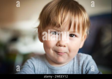 Ein glücklicher, süßer, lächelnder Junge fängt unsere Aufmerksamkeit mit seinem faszinierenden Blick ein, während er direkt in die Kamera schaut. Freude und Glück Konzept. Liebe und f Stockfoto