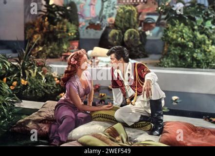 Ein Porträt von Piper Laurie und Tony Curtis mit dem Film Son of Ali Baba (1952). In diesem abenteuerlichen Film, der im alten Persien spielt, spielt Curtis Kashma Baba, den temperamentvollen und gewagten Sohn des legendären Ali Baba, während Laurie Prinzessin Azura darstellt, eine Figur, die willensstark und bezaubernd zugleich ist. Der Film ist bekannt für seine Mischung aus Romantik, Action und Curtis berühmter Zeile: „Dort liegt das Schloss meines Vaters“. Stockfoto