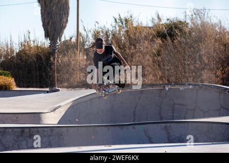 Anmutige Skate-Moves: Ein schicker Skater gleitet und springt mühelos in die pulsierende Energie des Skate-Parks. Stockfoto