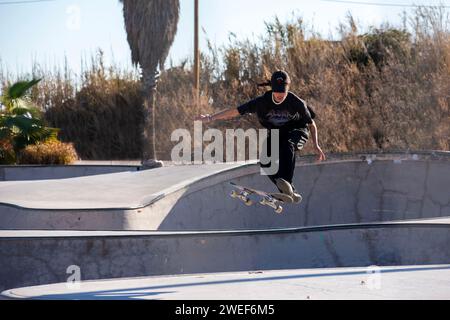 Anmutige Skate-Moves: Ein schicker Skater gleitet und springt mühelos in die pulsierende Energie des Skate-Parks Stockfoto