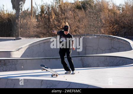 Anmutige Skate-Moves: Ein schicker Skater gleitet und springt mühelos in die pulsierende Energie des Skate-Parks Stockfoto