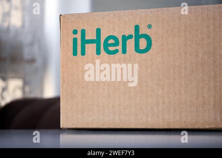Braune Kartonschachtel mit grüner Logo-Aufschrift iHerb zu Hause, auf dem Tisch. Online-Bestellung, Einkauf, Kauf von Vitaminen und Kosmetika. Empfangen des p Stockfoto