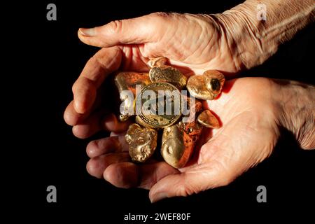 bitcoin-Münzen und Goldnuggets in den Palmen älterer Frauen Stockfoto