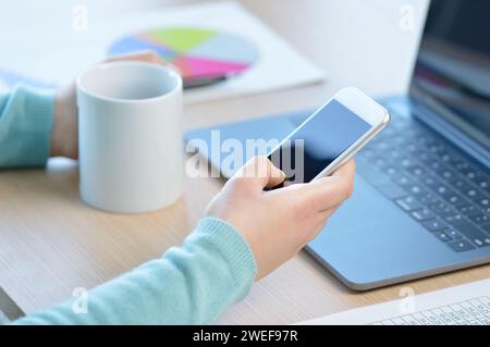 Freigestellte Aufnahme einer unbekannten Geschäftsfrau, die ein Handy in ihrem Heimbüro benutzt Stockfoto