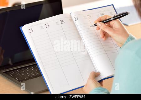 Zugeschnittene Aufnahme einer unbekannten Geschäftsfrau, die sich Notizen in ein Notizbuch in ihrem Heimbüro schreibt Stockfoto