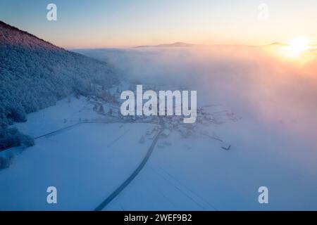 Blick aus der Vogelperspektive auf ein wunderschönes kleines Dorf auf dem Land in der Nähe des Kurorts Dolenjske toplice in den frühen Morgenstunden, kurz nach dem Schneefall, slowenien Stockfoto