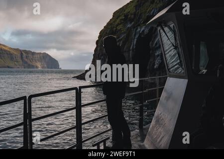 Silhouette eines Mannes, der auf einem Boot segelt und tagsüber in der Nähe des Wassers steht? Stockfoto