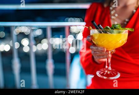 Frau in rotem Kleid trinkt Mango-Daiquiri-Cocktail. Stockfoto