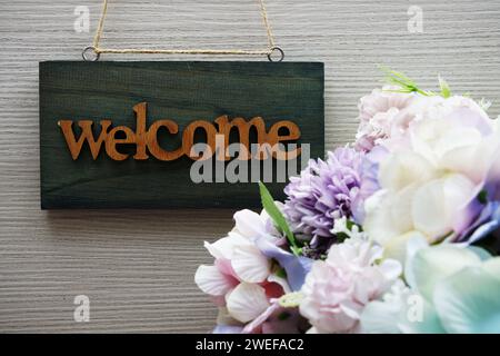 Begrüßungsschild und Blumenstrauß auf Holzhintergrund Stockfoto