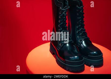 Schwarze Damen-Schnürschuhe aus Lackleder auf einem Boutique-Stand auf rotem Hintergrund Stockfoto