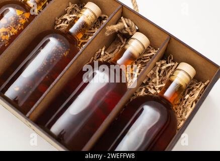 Flaschen mit teurem selbstgemachtem Alkoholbrand und Cognac in einer Holzkiste, Nahaufnahme. Stockfoto