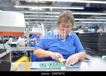 Freundliche Frau in einem mikroelektronikfertigung Factory-Komponenten Montage und Löten arbeiten Stockfoto