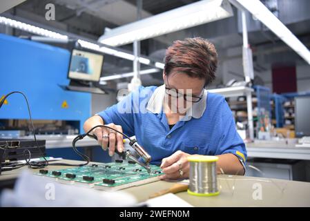 Freundliche Frau in einem mikroelektronikfertigung Factory-Komponenten Montage und Löten arbeiten Stockfoto