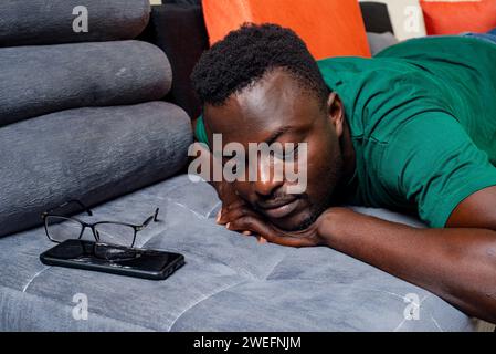 Junger müder Mann, der zu Hause auf dem Sofa schläft. Stockfoto