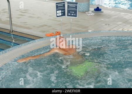 Ein älterer Mann entspannt sich in einem Swimmingpool mit Hydromassage. Urlaubskonzept. Stockfoto