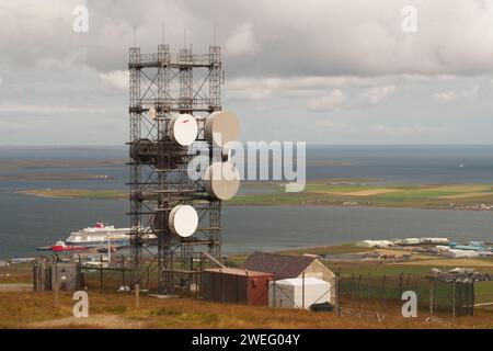 Übertragungsmast in Wideford Hill, Kirkwall, Orkney, Schottland, Großbritannien, mit der Fähre von Aberdeen, die am Pier unten liegt Stockfoto