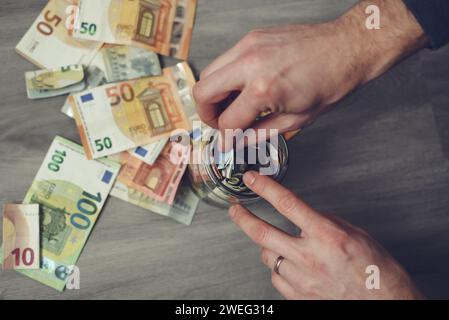 Man zählt und steckt Geld in das Glas Stockfoto