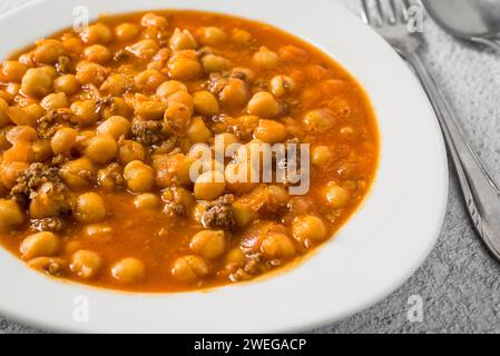 Kichererbseneintopf mit Hackfleisch auf einem weißen Porzellanteller auf einem Steintisch Stockfoto