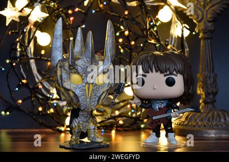 Funko Pop Actionfiguren von Sauron vom Herr der Ringe und Eddie von Stranger Things. Orangefarbene Beleuchtung, schwarzer Hintergrund, dunkler Ort. Stockfoto