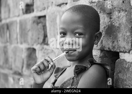 Ein 11-jähriges ugandisches Mädchen lächelt und hält einen Stift. Stockfoto