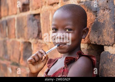 Ein 11-jähriges ugandisches Mädchen lächelt und hält einen Stift. Stockfoto