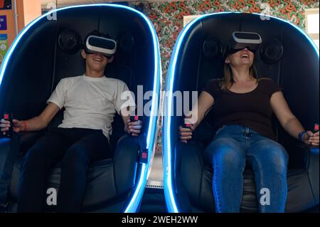 Virtual-Reality-Attraktion: Sohn und Mutter erleben Adrenalin aus Virtual-Reality-5D-Sensation. Stockfoto