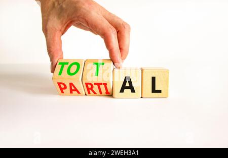 Symbol „Gesamt“ oder „Teil“. Geschäftsmann verwandelt wunderschöne Holzwürfel und ändert das Wort Partial in Total. Schöner weißer Tisch mit weißem Hintergrund. Busin Stockfoto