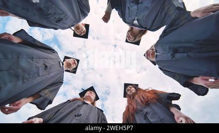 Studenten stehen in einem Kreis in schwarzen Gewändern. Stockfoto