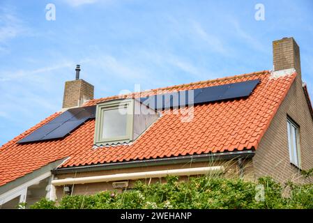 Solarpaneele zur Stromerzeugung auf dem Dach eines modernen Backsteinhauses Stockfoto