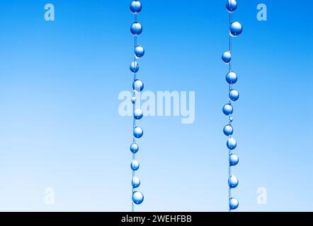 Kleine blaue Wassertropfen hängen an der Angelschnur, Makroaufnahme Stockfoto