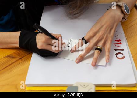 Nahaufnahme der Hände einer erfahrenen Kalligraphin, die Schreiben in italienischer Sprache und im alten Stil praktiziert, das Datum 26. Oktober, auf einem Sketchbo Stockfoto